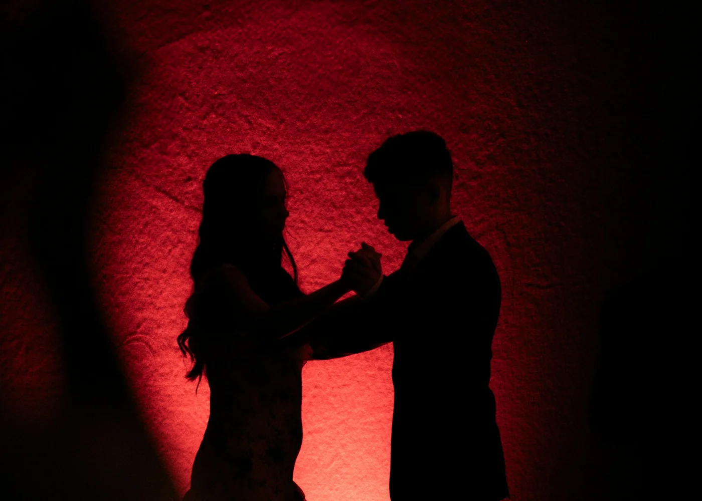 The silhouette of a tango couple dancing under red stage light, representative of the show's lighting
