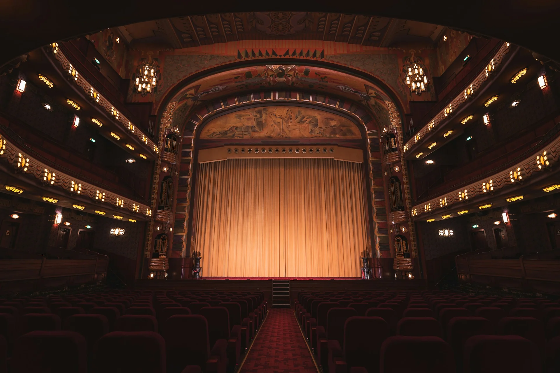 The gold-curtained stage and tiered balconies of a restored Art Deco theatre, representative of Tango Porteño's converted cinema auditorium