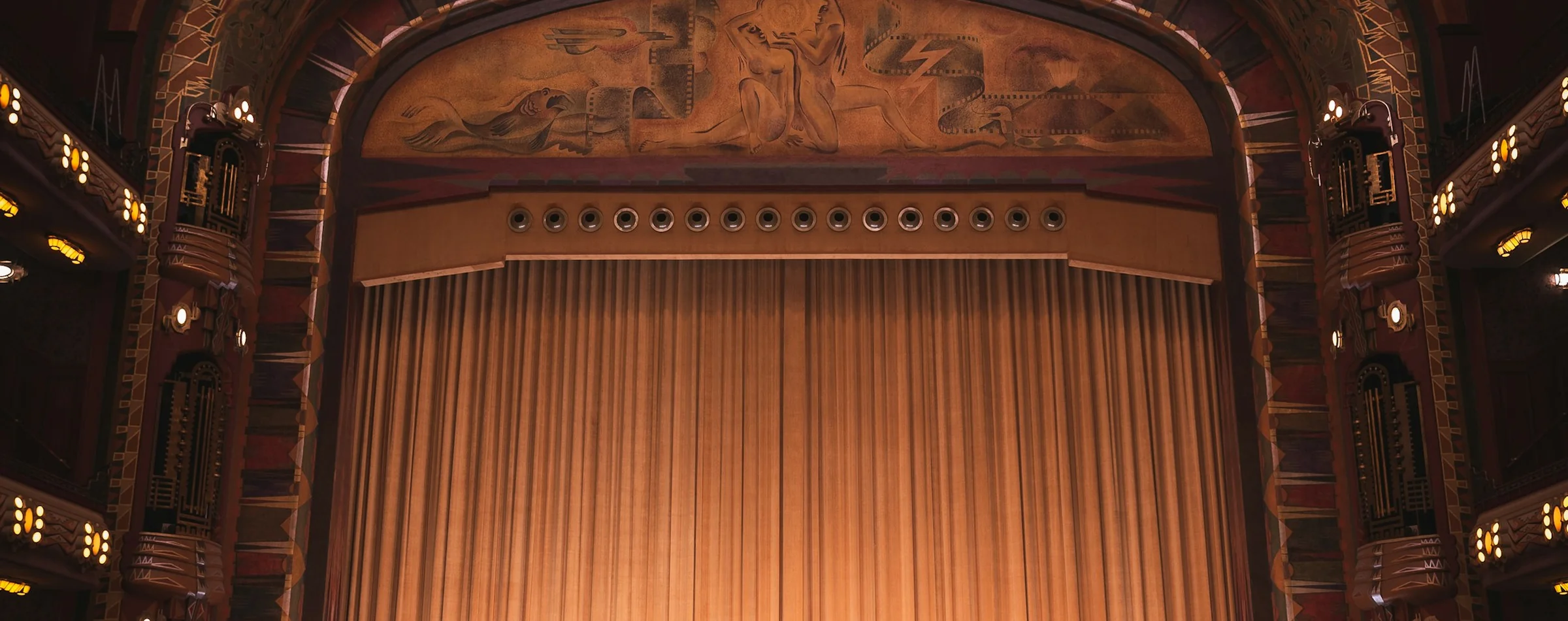 An Art Deco relief and gold curtain above a theatre stage, representative of the original 1956 proscenium at Cerrito 570